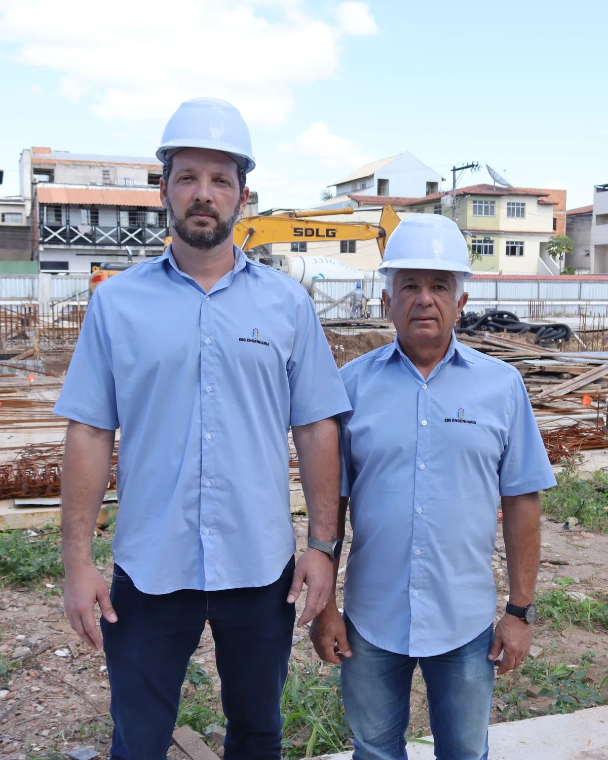 Estevão Barbosa de Souza e o pai, Oscar César Montenegro de Souza, de capacete e camisa da EBS em um canteiro de obra